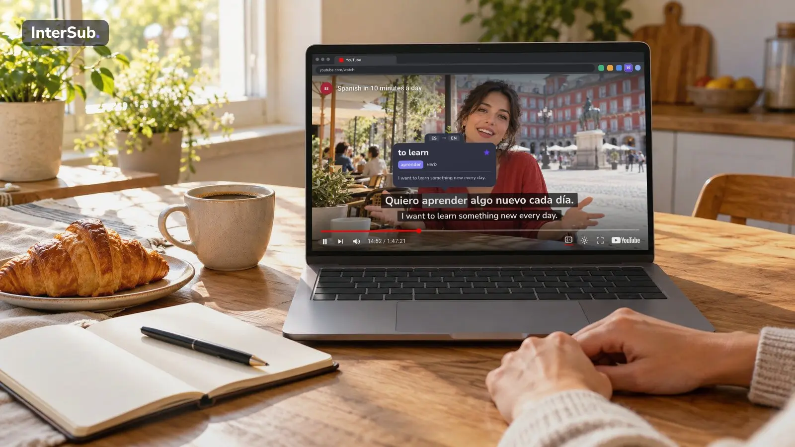A Spanish teacher's YouTube video plays in the browser on a laptop at a breakfast table, with Spanish and English subtitles; the InterSub dictionary shows “aprender: to learn”