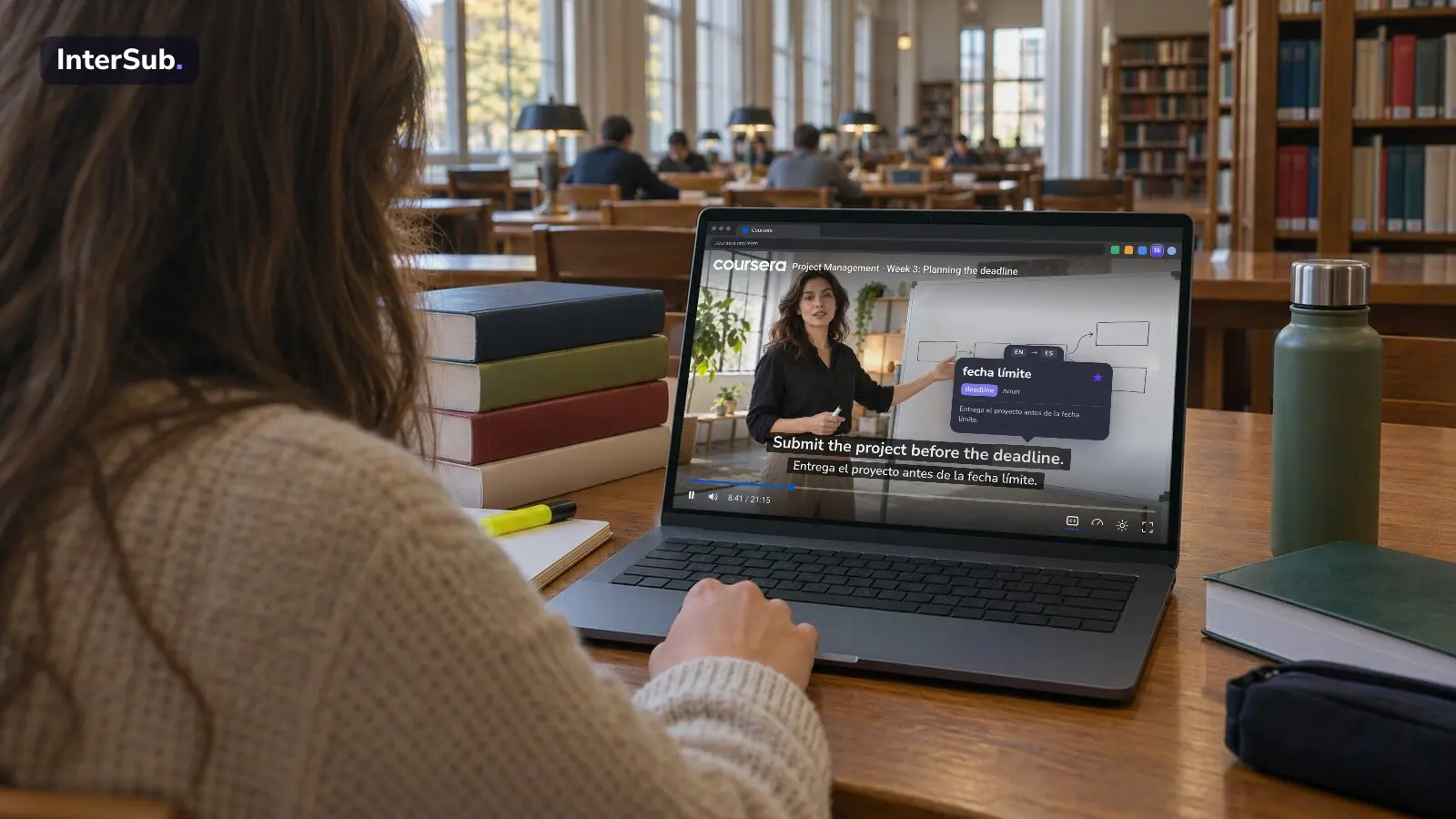 A student in a library watches a Coursera lecture in the browser on a laptop, with English and Spanish subtitles; the InterSub dictionary shows “deadline: fecha límite”