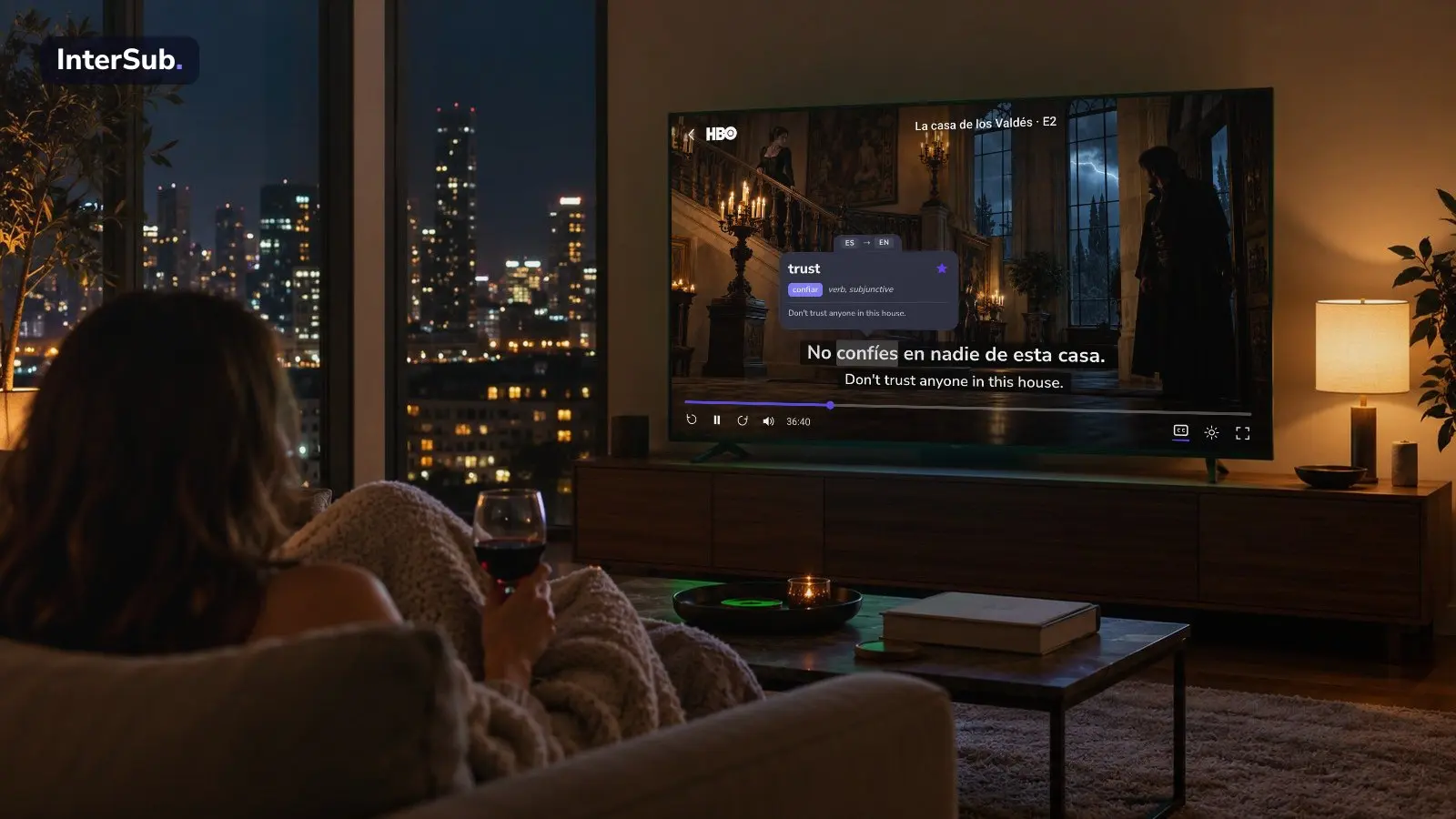 A woman with a glass of wine watches a candlelit period drama on HBO Max on a big TV at night, with Spanish and English subtitles; the InterSub dictionary shows “confíes: trust”